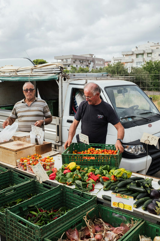 A group of men standing around a table filled with vegetables