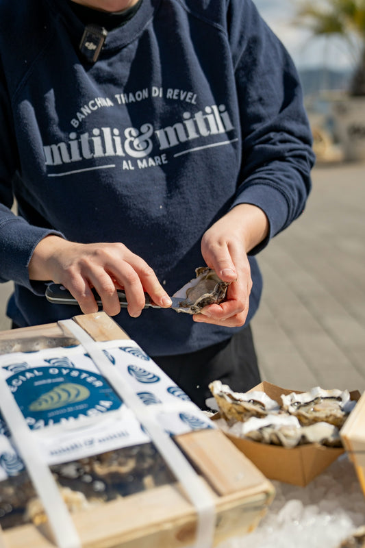 Someone is shucking oysters at an outdoor market.