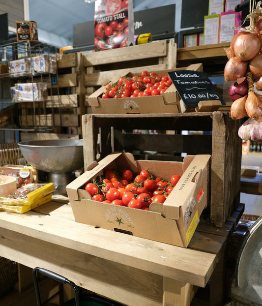 Fresh tomatoes displayed in cardboard boxes at a market.